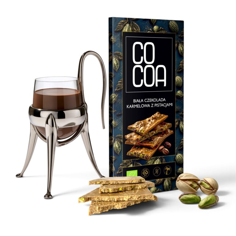 Biała czekolada karmelowa z pistacjami COCOA obok szklanki czekolady do picia